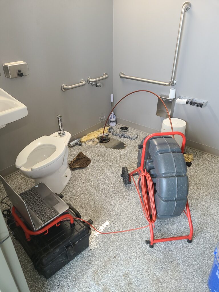 a pipe cleaning tool snaking a drain in a bathroom