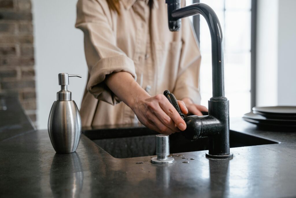 person touching handle of kitchen sink